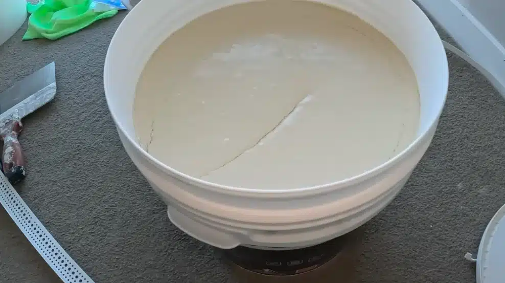 Bucket of joint compound ready for drywall restoration, part of what to do when fixing burst pipe water damage at home